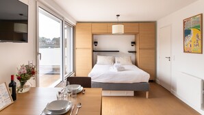 Una camera d'albergo moderna con un letto, un comodino e una grande finestra.