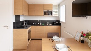 Una cucina moderna con mobili in legno, un piano di lavoro nero e un'area pranzo con un tavolo apparecchiato per due.