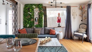 A modern living room with a green wall, a wooden coffee table, and a sofa with cushions.