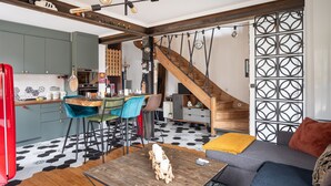 A modern kitchen with a dining area, a staircase, and a living room with a sofa and coffee table.