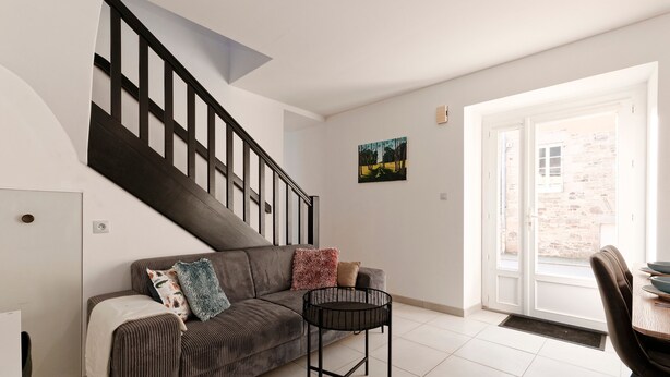 A modern living room with a sofa, a coffee table, and a staircase. - La Caulnaise - Maison climatisée avec terrasse (Caulnes)