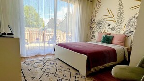 A bedroom with a bed, a desk, a chair, and a view of the outside. - La Caulnaise - Maison climatisée avec terrasse (Caulnes)