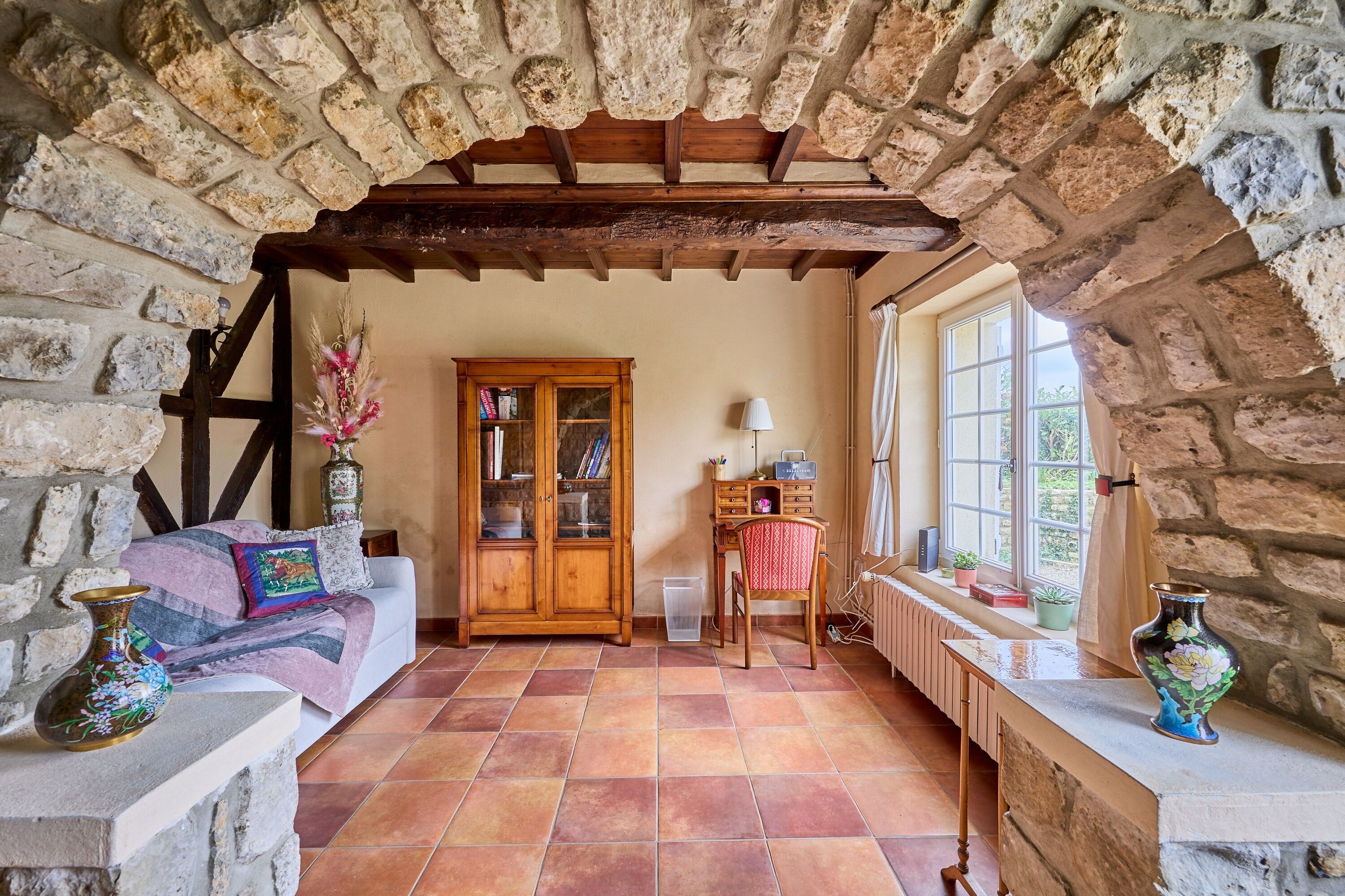A cozy room with a stone fireplace, a wooden cabinet, and a sofa.