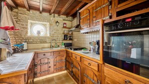 Cocina con armarios de madera, pared de piedra, una ventana y un horno Siemens.