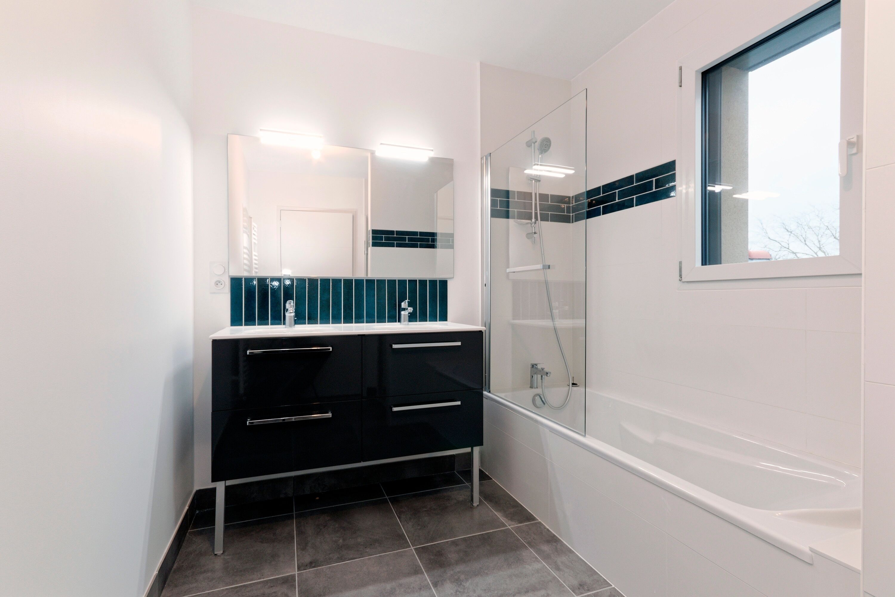 Een moderne badkamer met een douchecabine van glas, een witte badkuip en een zwart badmeubel met lades.