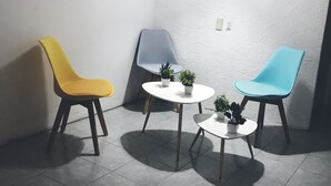 Un petit patio clos, aménagé avec trois chaises et deux petites tables, dont l’une est ornée de plantes en pot.