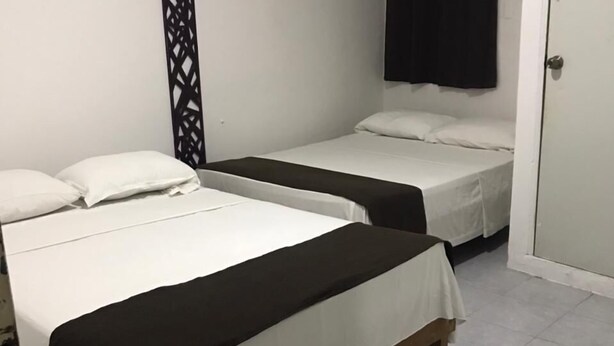 Une chambre avec deux lits, un panneau décoratif noir, un appareil de climatisation blanc et un rideau noir.
