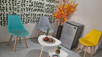Una habitación con tres sillas, una mesita pequeña y una planta decorativa.
