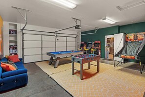 A recreational room with a pool table, foosball table, and a basketball arcade.