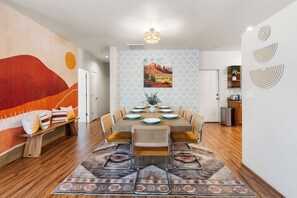Un coin repas avec une table en bois dressée pour six personnes, entourée de chaises dotées d’assises rembourrées.