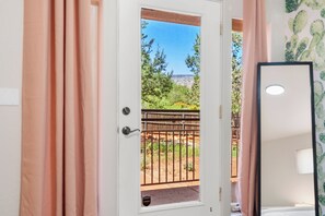 Una habitación con puerta que da a un espacio exterior con valla de madera y vegetación.