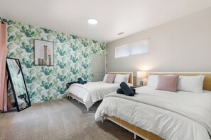 Habitación de hotel con dos camas, un ventanal grande, una lámpara de techo y una pared con diseño de cactus.
