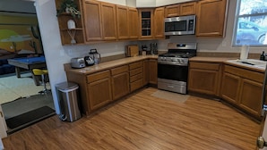 A modern kitchen with wooden cabinets, stainless steel appliances, and a wooden floor.