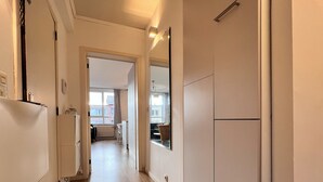 A hallway with a refrigerator, cabinets, and a view into a dining area. - Bright & Stylish in Nature (Brussels)