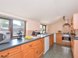 A modern kitchen with wooden cabinets, a dishwasher, a stove, and a sink.