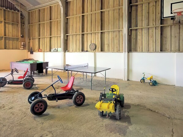 A spacious indoor area with a ping pong table, a small table, and various children's toys.