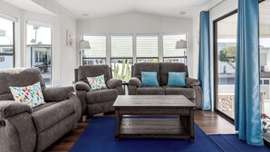 Una sala de estar con dos sofás grises, una mesa de centro de madera y una alfombra azul.