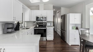 Una cocina moderna con armarios blancos, horno empotrado, microondas y refrigerador.
