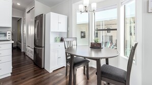 Una cocina moderna con armarios blancos, un refrigerador de acero inoxidable y una mesa de comedor con sillas.