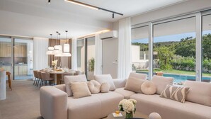 A modern living room with a beige sofa, a dining area, and a view of a swimming pool. - Villa ZaLú with Heated Pool (Srinjine)