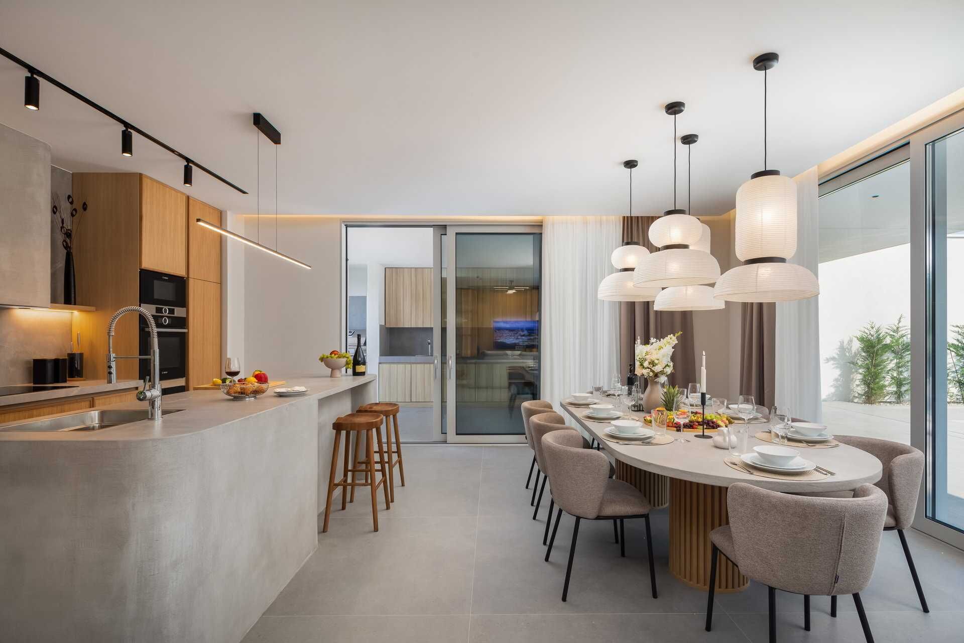 Una cocina moderna con una isla central, taburetes de bar e iluminación colgante.