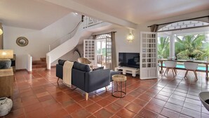 Un grand espace de vie comprenant un escalier, un canapé, un téléviseur et une table à manger avec des chaises.