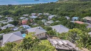 A residential area with houses, a swimming pool, and a view of the ocean and a mountain. - Domaine Agapé - Four Bedroom Villa, Sleeps 9 (Le Diamant)