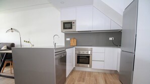 Una cuina moderna amb armaris blancs, electrodomèstics d'acer inoxidable i un sòl de fusta.