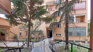 A multi-story residential building with balconies, a central staircase, and surrounding greenery. - TM APARTMENT (Roma)