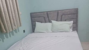 A bed with a grey headboard and white bedding in a room with light blue walls. - Thé good stay 3 midelt

 (Midelt)
