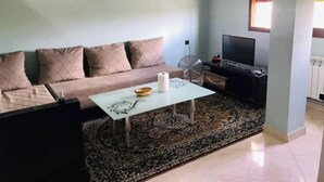 A living room with a sofa, a coffee table, a TV, and a fan. - Thé good stay 3 midelt

 (Midelt)