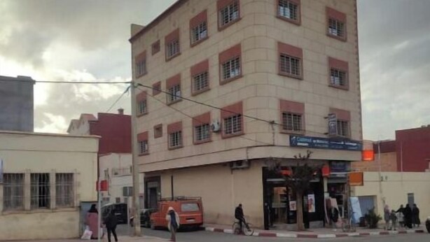 A multi-story building with a flat facade, several windows, and a ground-level entrance. - Escale. 1!!

 (Midelt)