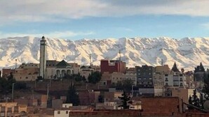 A mountainous landscape with snow-capped peaks in the background and a cityscape in the foreground. - Escale. 1!!

 (Midelt)