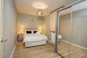 Une chambre à coucher avec un lit, des lampes de chevet, un radiateur et une porte coulissante.