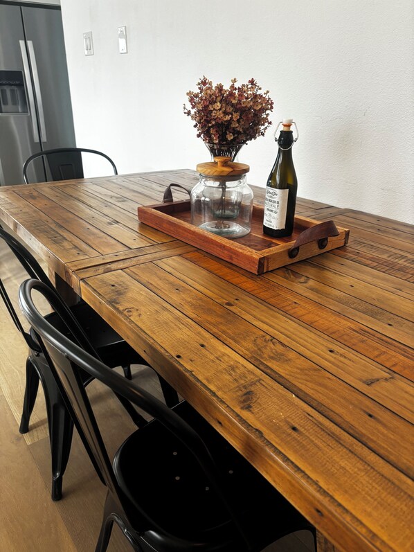 A wooden dining table with a glass jar, a bottle, and a wooden tray.