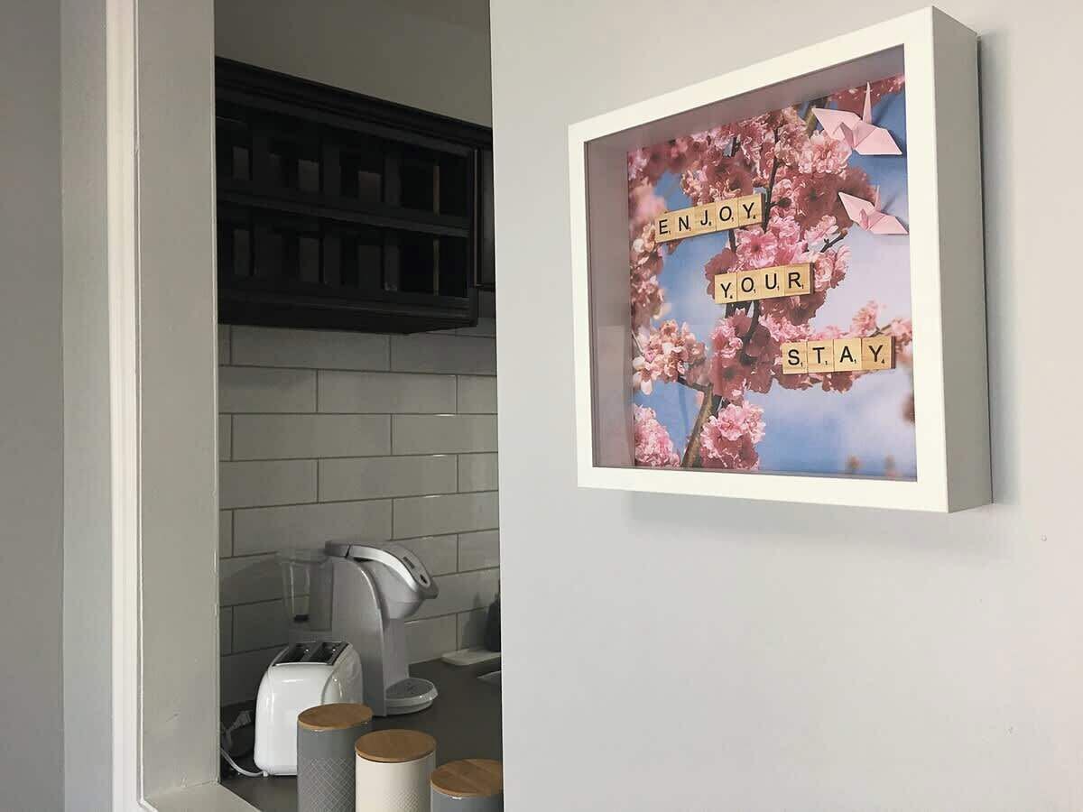 A kitchen with a framed picture on the wall, a toaster, a kettle, and a blender on the counter.
