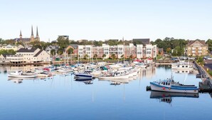 Un port esportiu amb vaixells amarrats, una església amb dues agulles i edificis residencials al fons.