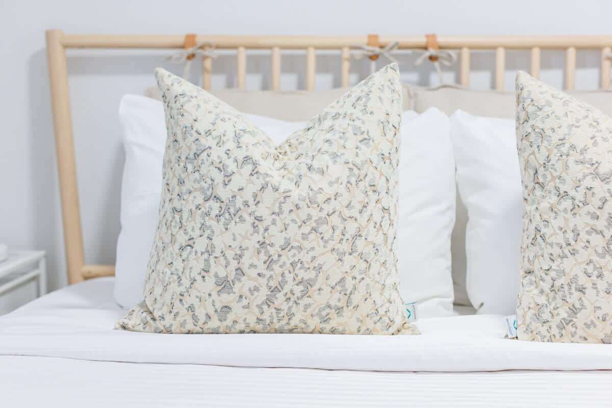 Ein Bett mit Holz-Kopfteil und Kissen mit Blumenmuster.