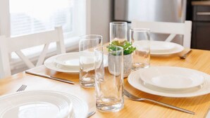 A dining table set with white plates, clear glasses, and a small potted plant. - 67 - Walking distance to downtown (Charlottetown)