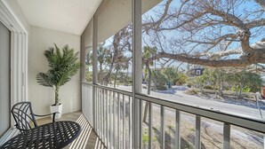 A balcony with a potted plant, a metal table, and chairs.