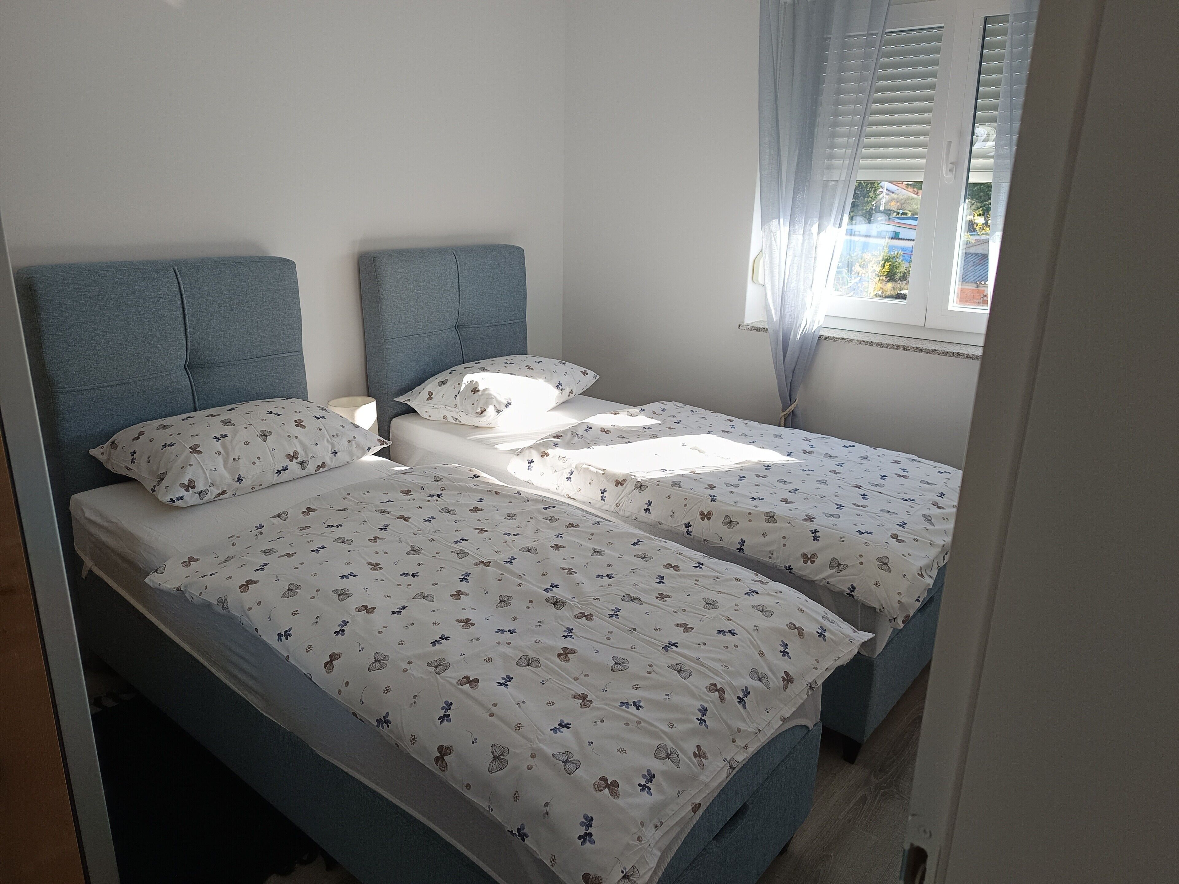 A bedroom with two beds, each with a headboard and a floral-patterned bedspread.