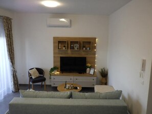 A living room with a sofa, a coffee table, a TV, and decorative shelves.