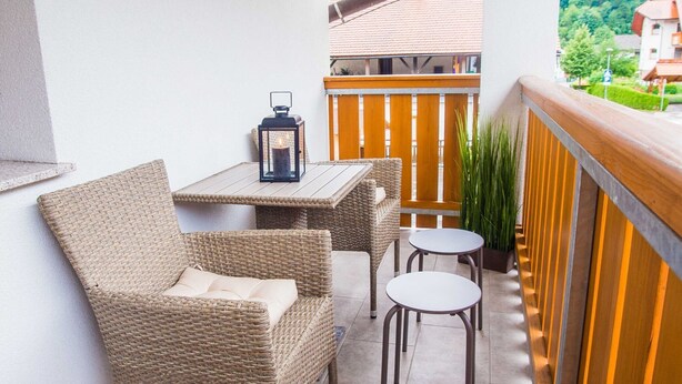 Un balcon agrémenté de meubles en osier, d’une table et de deux chaises.