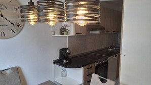 Une cuisine moderne avec une horloge en bois, des luminaires suspendus, une machine à café et un évier.