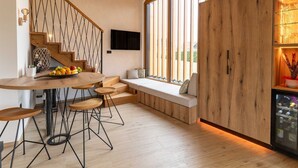 A modern kitchen with a wooden staircase, a dining area with stools, and a built-in seating area with a view of the outdoors.