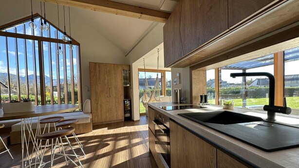 Eine moderne Küche mit Holzschränken, einem großen Fenster und einer hängenden Lampenleuchte.