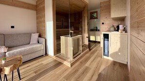Una sala de estar moderna con piso de madera, un sofá gris y un separador de vidrio.