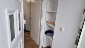 A narrow hallway with a wooden floor, white walls, and a door leading to a room. - Charming Rustic Apartments Brest - One Bedroom Apartment (Ig)