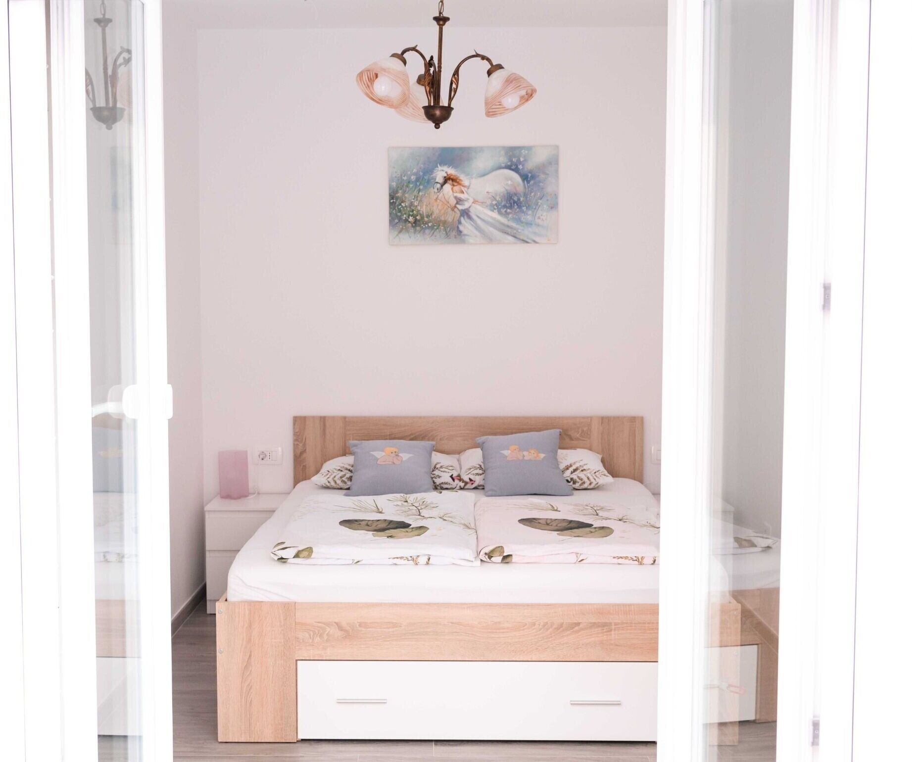 A bedroom with a wooden bed, floral bedding, and a painting of a horse on the wall.
