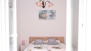 A bedroom with a wooden bed, floral bedding, and a painting of a horse on the wall. - Izola Spacious Apartment with Terrace and Patio - Three Bedroom Apartment with Terrace (Izola)